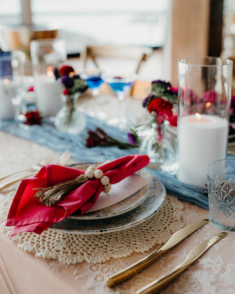 Decorative table setting with colourful cutlery, flowers, and plates on a tablecloth.