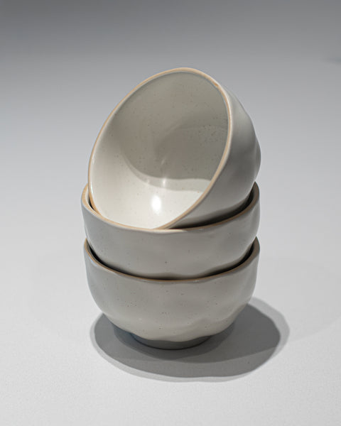 Stack of three gray ceramic bowls on a light gray background