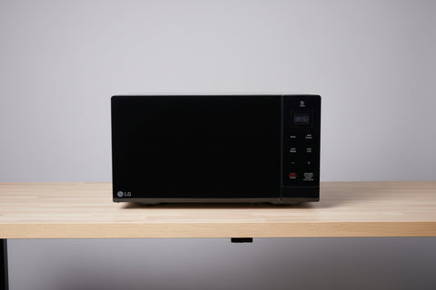 Black microwave on a metal table with a warehouse background
