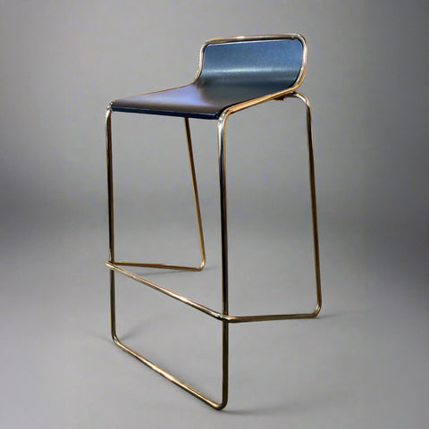 Bar stool with blue seat and gold metal frame on a gray background