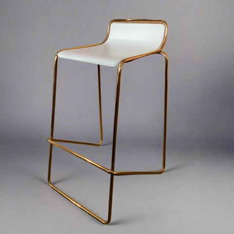 Bar stool with white seat and gold metal frame on a gray background