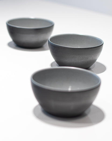 Three gray melamine bowls on a white background